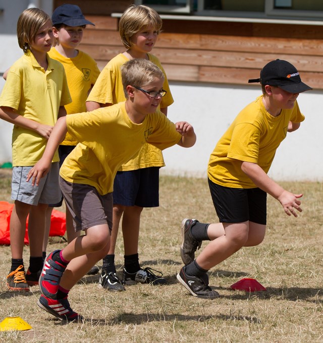 primary aged children in yellow t-shirts running across the playing field in a race