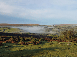 Landscape image of Dartmoor's rolling hills and blue sky.